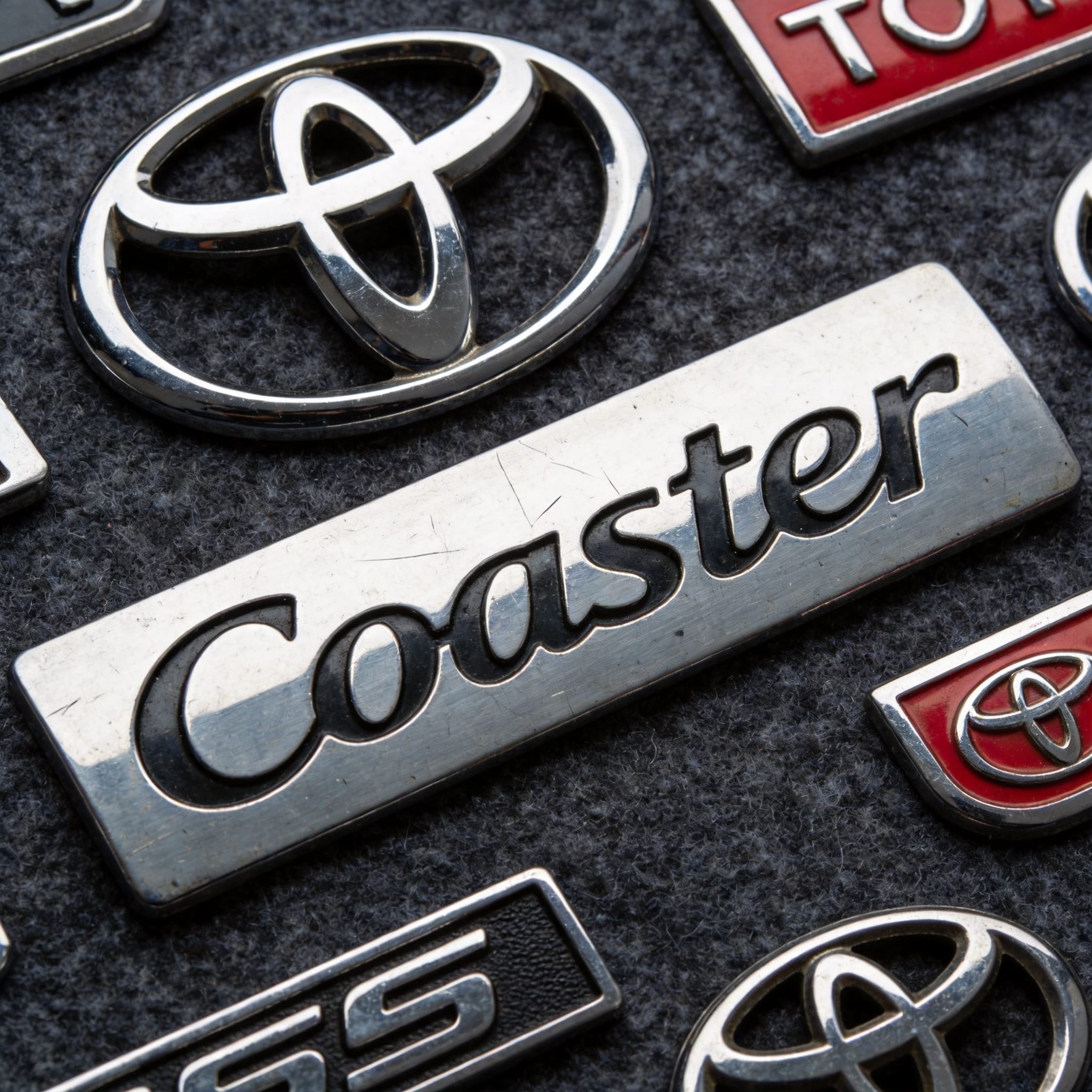 Close-up comparison of genuine versus counterfeit Toyota Coaster emblem